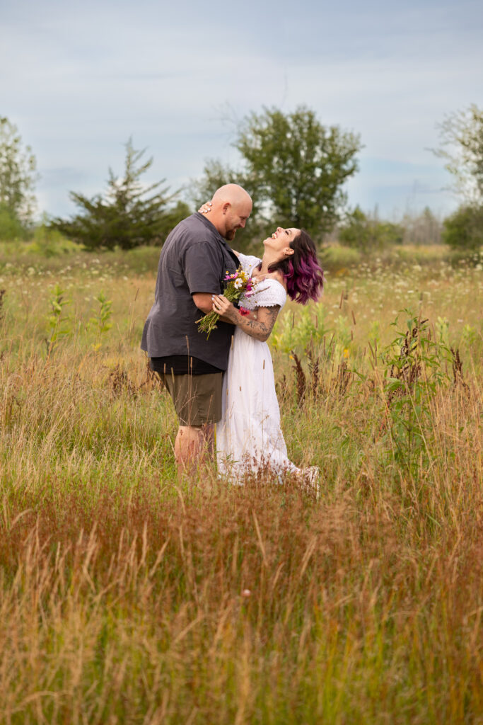 engaged couple laughing in a field of wildflowers