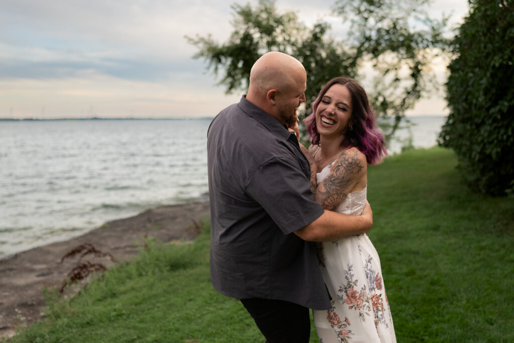 engaged couple laughing by the water